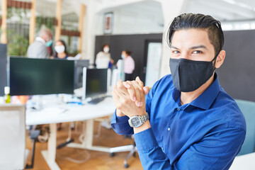 Fototapeta na wymiar Junger Business Mann im Büro mit Mund-Nasen-Schutz