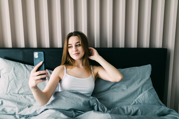 Beauty woman taking selfie from phone in the morning in bed