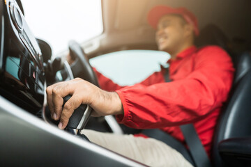 Red uniform hand control the stick shift transmission. Delivery man driving truck to send the parcel.