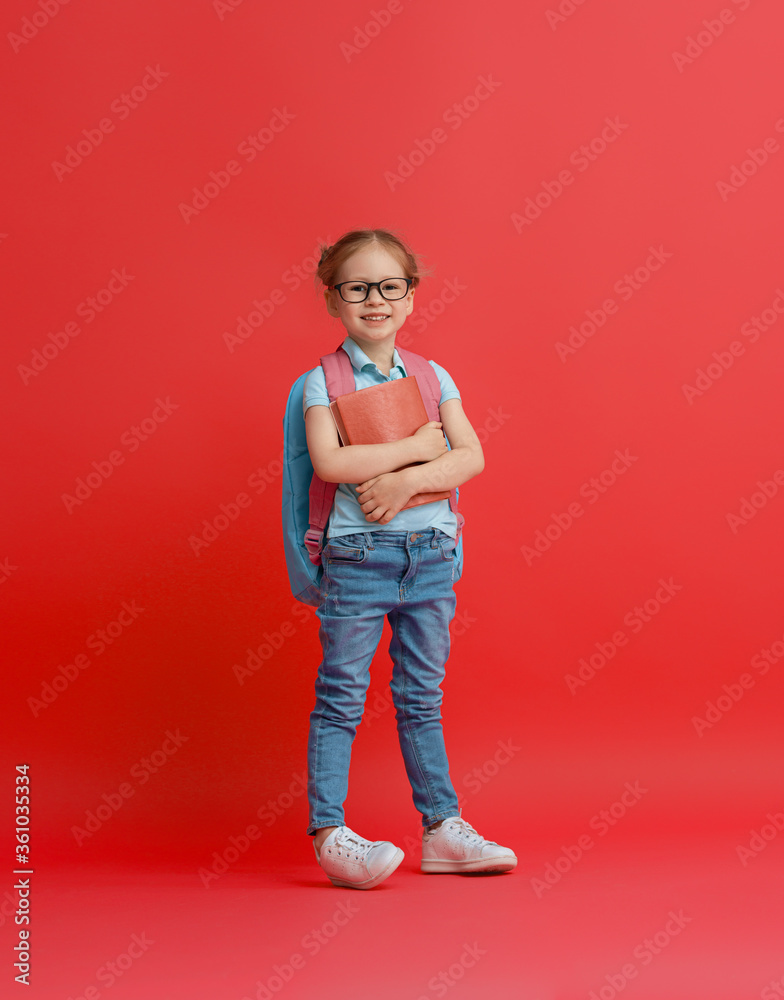 Wall mural kid with backpack on color background.