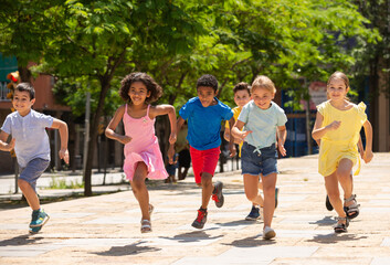 Obraz premium Team of positive kids running in race in the street and laughing