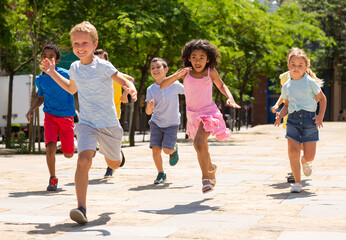 Fototapeta premium Group of joyful children running down the summer street