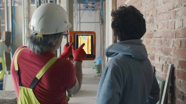 Back view of builder and owner check heat insulation with thermal camera