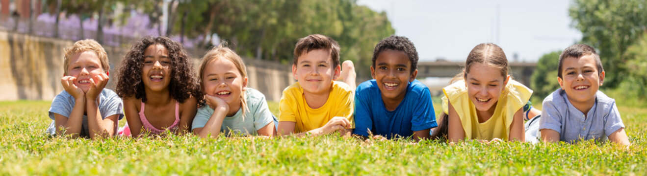 Portrait Of Smiling Children Who Are Posing Lying In Park