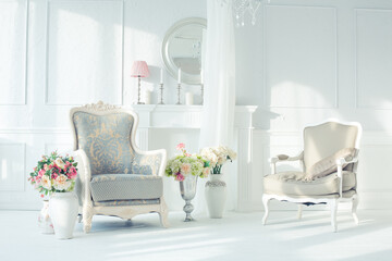 luxury clean bright white interior. a spacious room with sunlight and flowers in vases and royal...