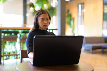 Obraz na płótnie Canvas Young beautiful Asian businesswoman using laptop at the coffee shop