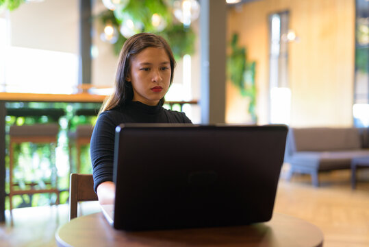 Young beautiful Asian businesswoman using laptop at the coffee shop