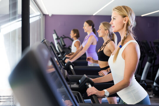 Slender athletic girls running on treadmill in fitness club