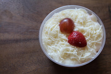fruit salad from pineapple, oranges, grapes and coconut with marshmallow and vanilla yogurt close-up on a plate. horizontal