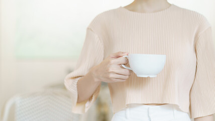 Cup of coffee. Woman hand holding tea or coffee. White cup of hot beverage in the morning.