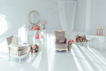 luxury clean bright white interior. a spacious room with sunlight and flowers in vases and royal chic furniture. 