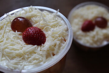fruit salad from pineapple, oranges, grapes and coconut with marshmallow and vanilla yogurt close-up on a plate. horizontal