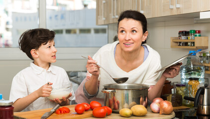 Smiling boy with mother preparing dinner