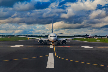 Airplane on the tarmac with runway and marking on the tarmac. Airplane rolls to takeoff. In the background clouds in the sky