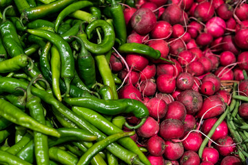 Red radish and hot chili peppers on market. Vegetables background.