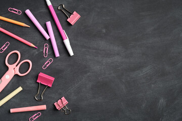 Pink school supplies on blackboard background. Flat lay, top view, copy space. Girl modern stationery, back to school concept.