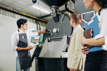 Entrepreneur showing equipment in his modern coffee roastery to inspectors
