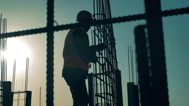 Construction worker is adjusting a carcass at sunset