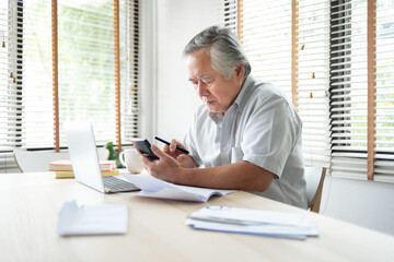 Stressed Asian Elderly male calculate family budget and Debt