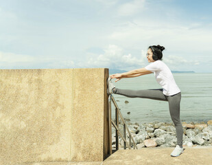 female doing stretching exercise for legs, Young fitness healthy woman warm up before running or jogging in the beach in sunshine on beautiful summer day. Sport fitness training outdoor concept.