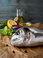 Dorado fish on the wooden  background with olive oil and spices.