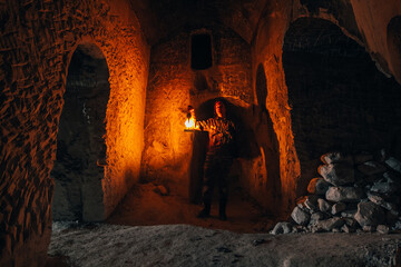 Man with kerosene lamp explores ancient abandoned underground monastery catacombs