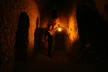 Man with kerosene lamp explores ancient abandoned underground monastery catacombs
