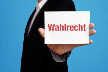 Wahlrecht. Geschäftsmann im Anzug hält Karte in die Kamera. Der Begriff Wahlrecht steht im Schild. Symbol für Business, Finanzen, Statistik, Analyse, Wirtschaft