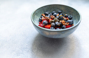 Bowl of healthy fresh berries salad on light blue background
