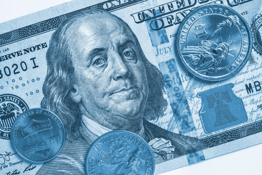 American money: a note of 100 US dollars, coin of 1 dollar, a quarter (25 cents) and a penny (1 cent). Blue tinted backdrop or wallpaper on a commercial, financial or banking theme. Top view. Macro
