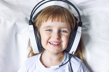 Portrait of a little laughing girl in headphones close-up, happy childhood, children's emotions