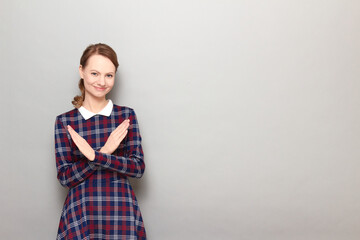 Portrait of happy girl making cross with hands and smiling joyfully