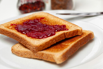 Crispy toasts covered with fruit jam served on kitchen table