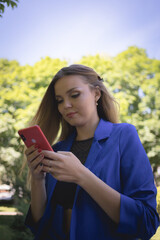 Fototapeta premium portrait of a beautiful white girl in a strict blue jacket with long hair with a phone in her hands. High quality photo