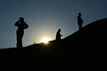 silhouette of men and a woman  on a hill top