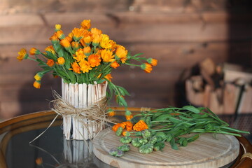 Calendula flowers in the vase and plant seeds on the small plate