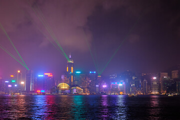 Fototapeta na wymiar Hong Kong skyline cityscape downtown skyscrapers over Victoria Harbour in the evening illuminated with lasers with tourist boat ferries . Hong Kong, China