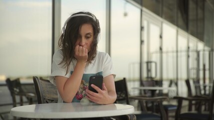 Obraz premium Young woman in headphones looking at the smartphone