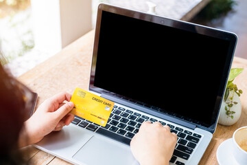 Close-up of freelance people business female Hand holding Credit cards casual working using with laptop computer with coffee cup in coffee shop like the background,Online payment shopping concept