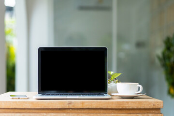 Mockup of laptop computer with empty screen with coffee cup and smartphone on table of the coffee shop background,Black screen