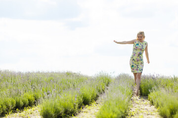 Naklejka na ściany i meble Woman standing with open arms on a lavender field