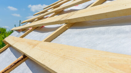 Wooden roof with rafter style framing against a blue sky