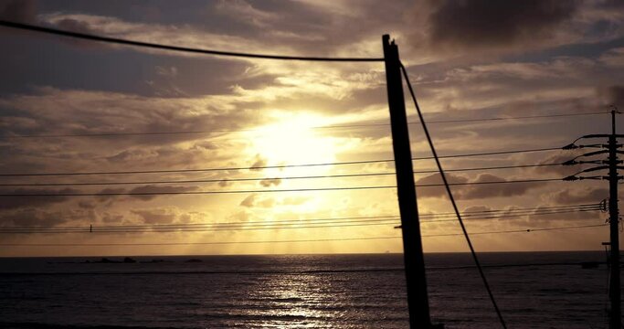 海岸線に沈む夕日　電柱のシルエット