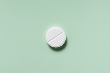 medicine, healthcare and pharmacy concept - white pill or capsule lies on mint green background top view copy space
