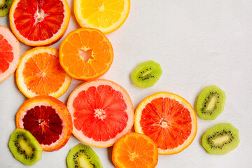 Bright juicy slices of orange, tangerines, grapefruit, kiwi and red orange on a light background, close-up. Top view