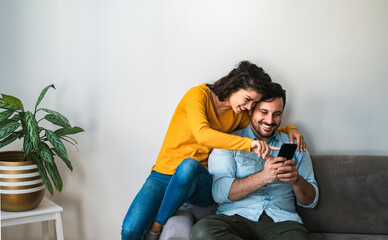 Smiling couple embracing while looking at mobile phone stock photo