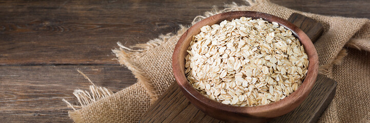 Oatmeal in a wooden bowl on a wooden table. raw oatmeal in a bowl. Banner	