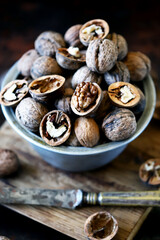 Fototapeta na wymiar Walnuts in a bowl on a dark background. Unpeeled walnuts. Inshell walnuts.