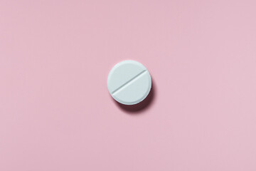 Fototapeta na wymiar medicine, healthcare and pharmacy concept - white pill or capsule lies on pink background top view copy space