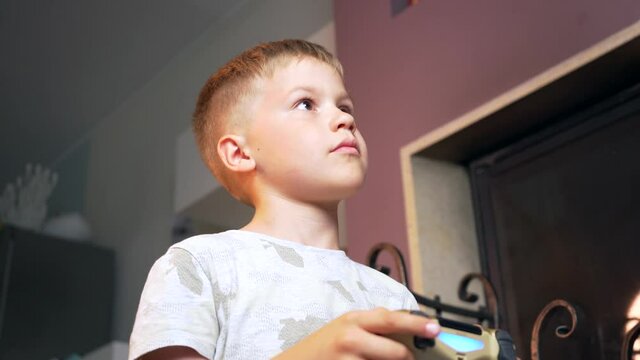 Focused Child Learning to Play Video Games at Home. Small Boy Holding a Computer Game Controller in Hands and Playing Console Indoors. Focused and Involved Facial Expression. 